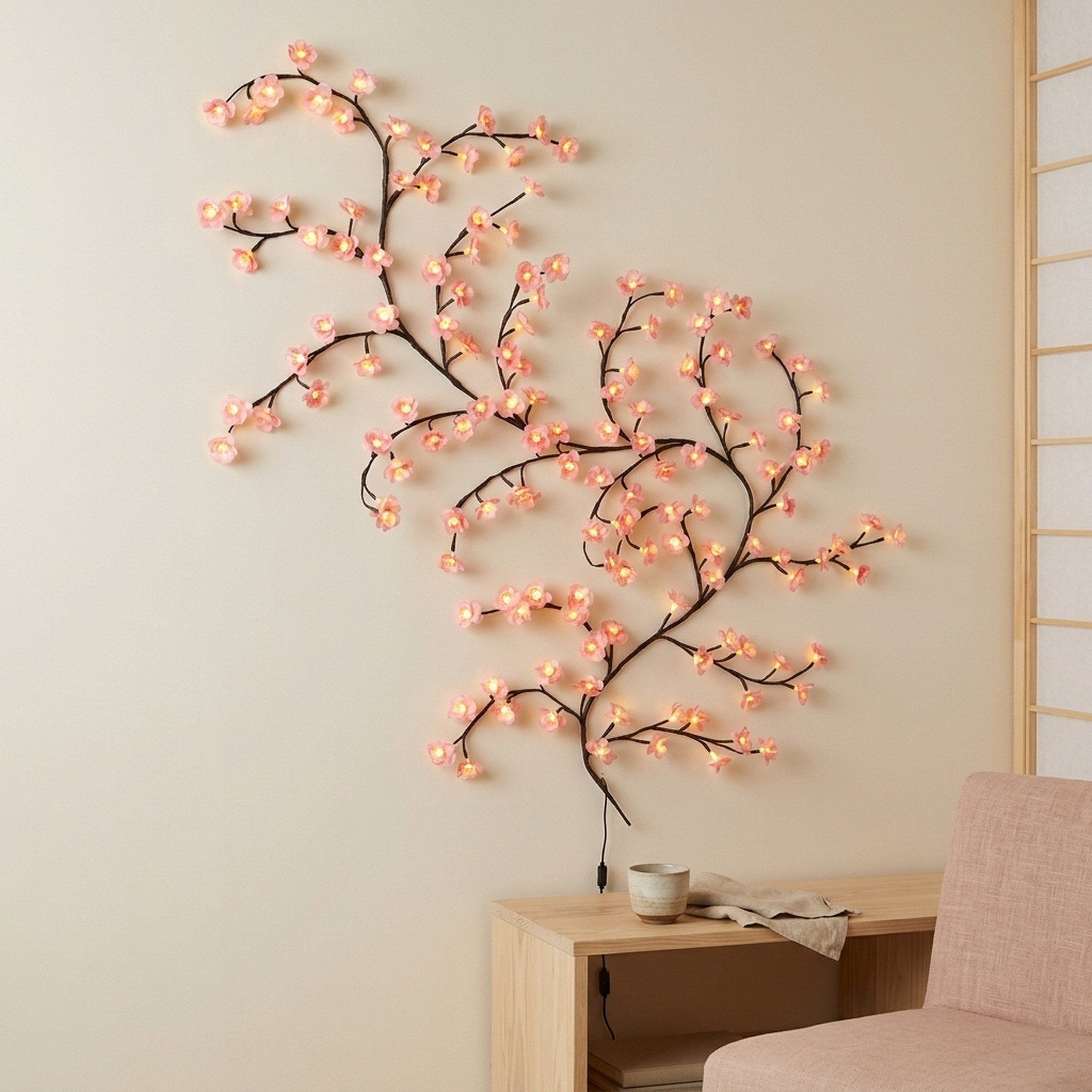 Pink blossom vine by a tea table in a calm Japanese-inspired room